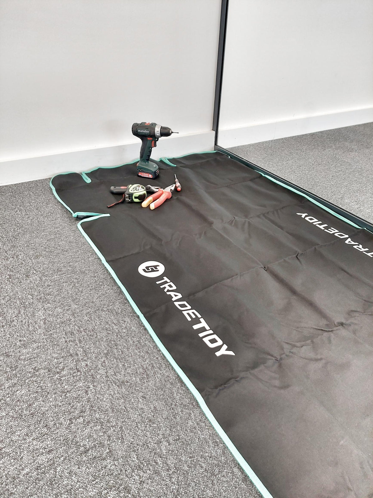 Black mat with 'TradeTidy' branding on a grey floor.