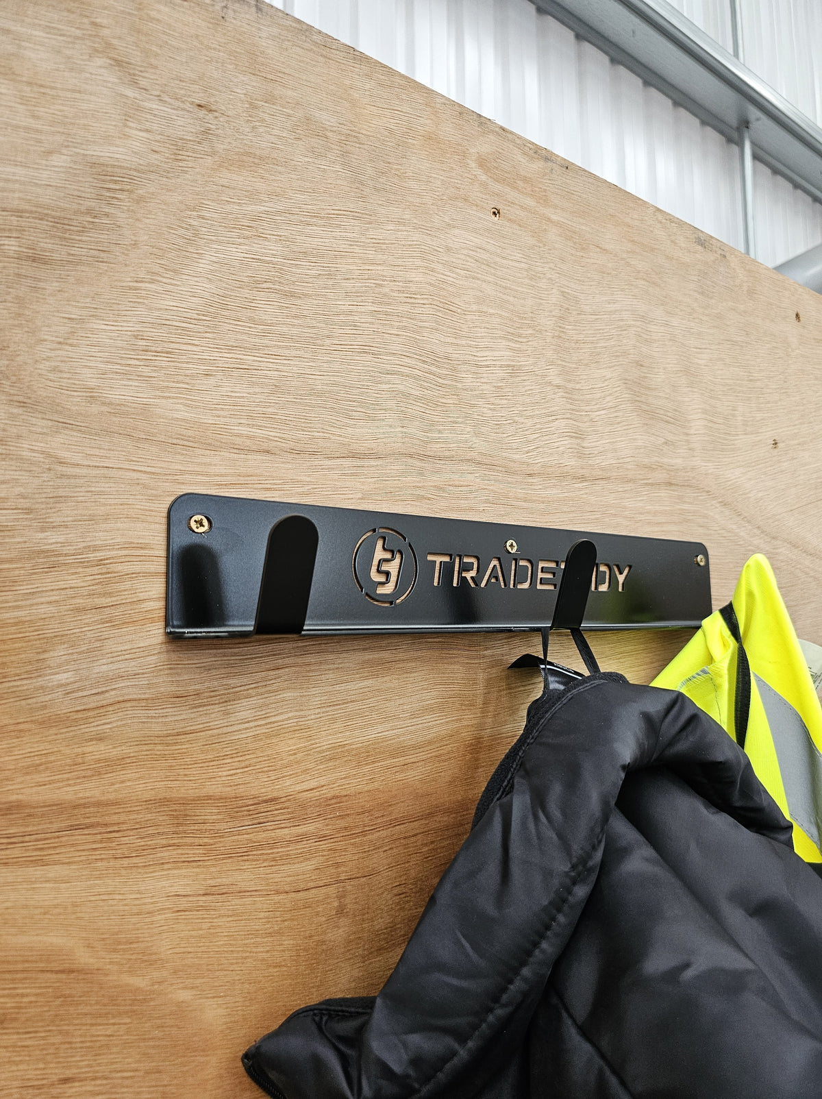 TradeTidy - Black Coat Hanger mounted on a wooden wall with jacket hanging