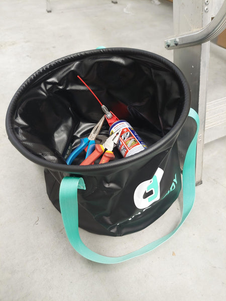 TradeTidy - Collapsible bucket with teal strap containing tools on a concrete floor