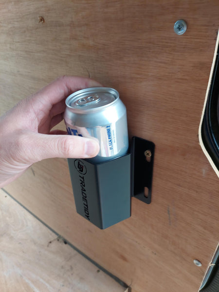 Hand holding a can in a black TradeTidy can holder on a wooden surface