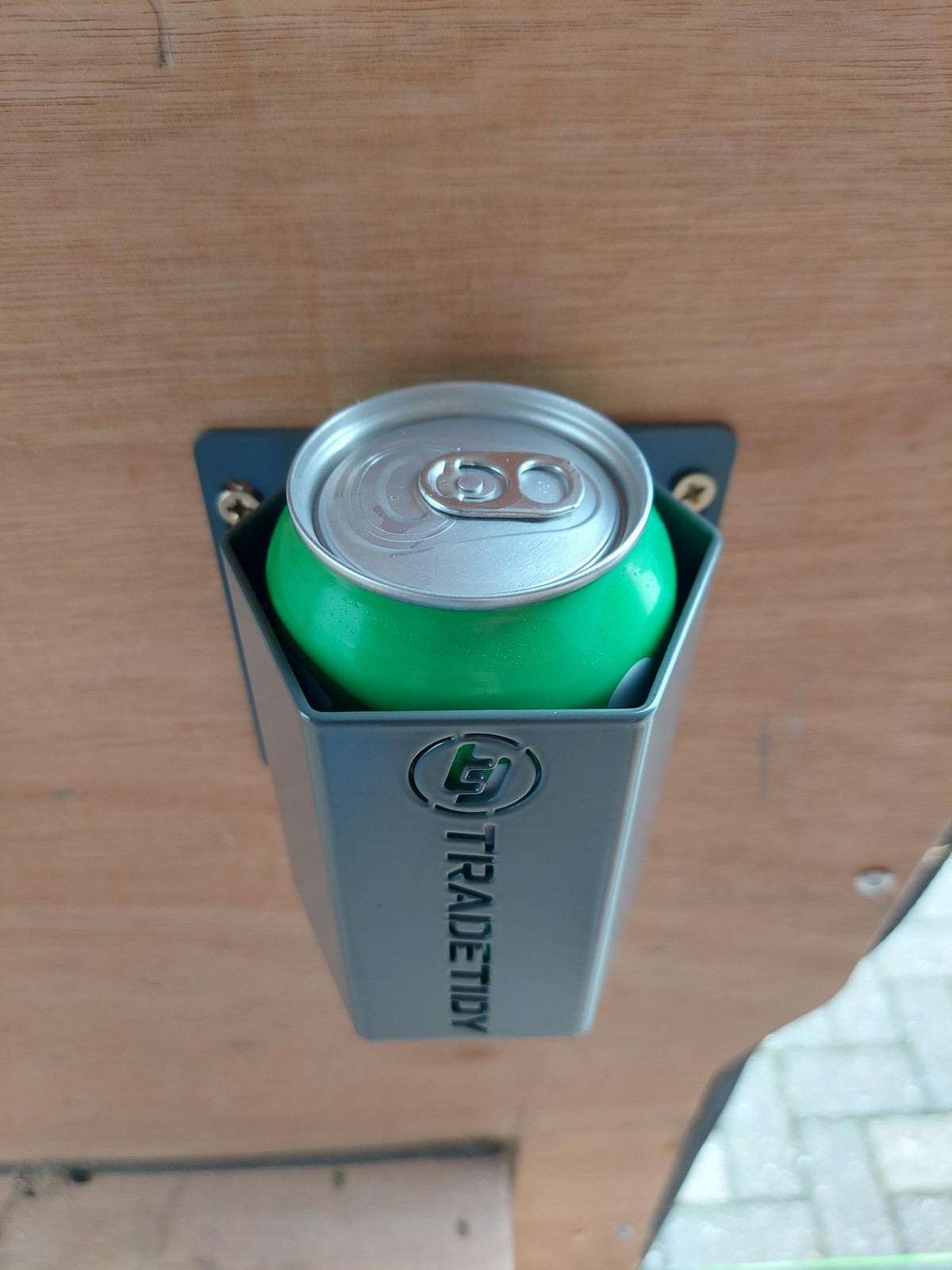 Green can inserted into a can holder labeled 'TradeTidy' on a wooden surface.