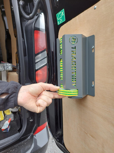 Hand holding a roll of green and yellow tape next to a metal bracket with 'TradeTidy' branding.