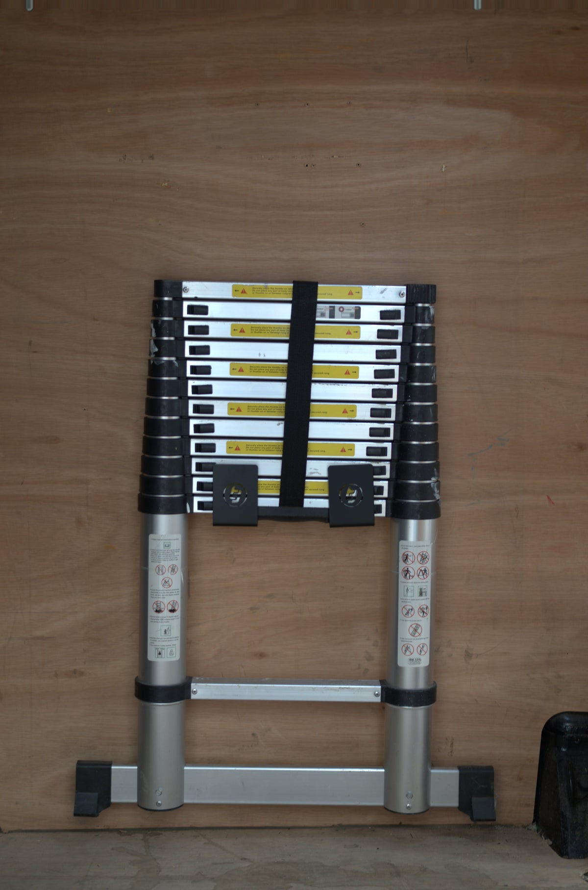TradeTidy - telescopic ladder in a black ladder bracket on a wooden wall