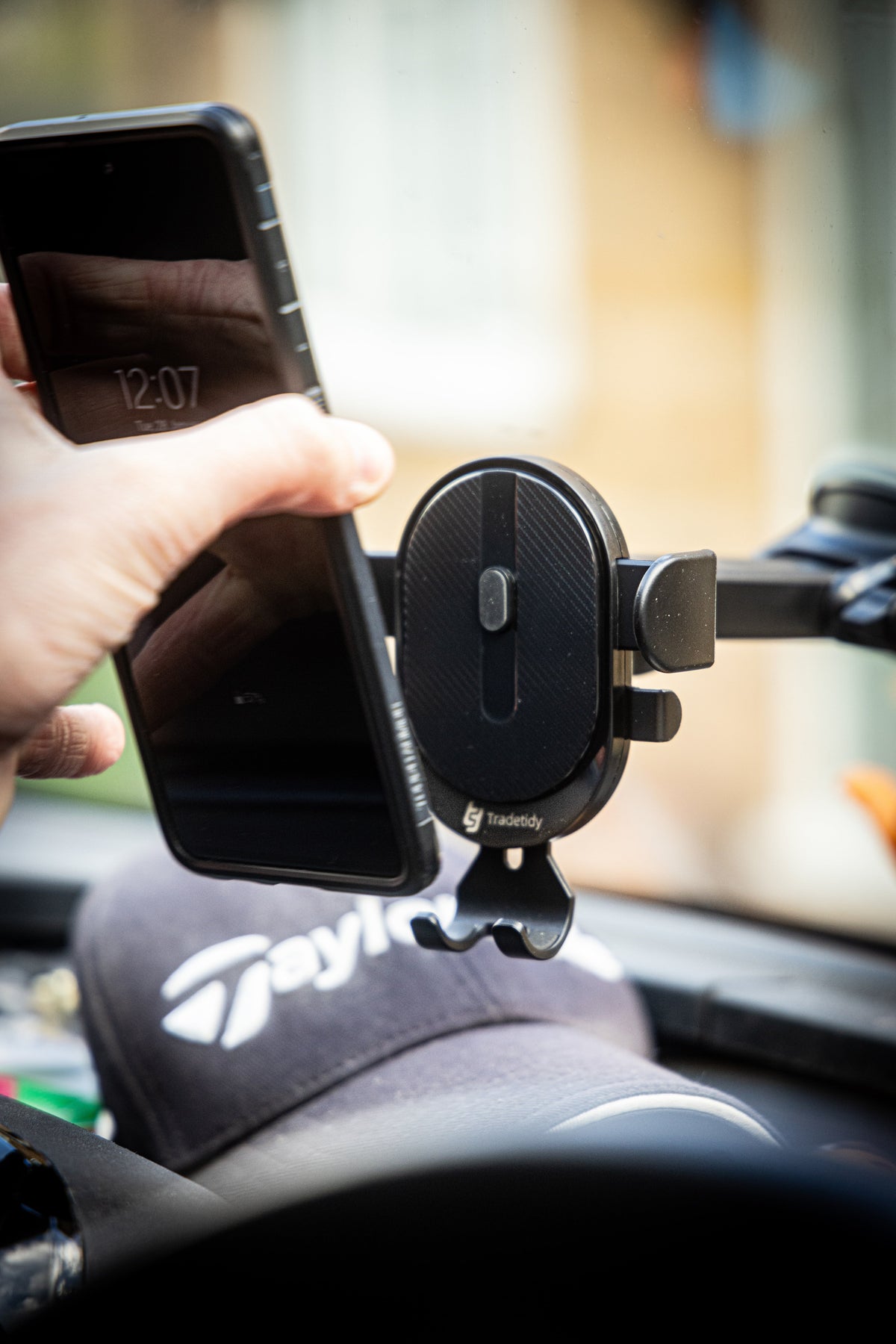TradeTidy - A mobile phone holder mounted on a dashboard, with a hand adjusting the phone's position.