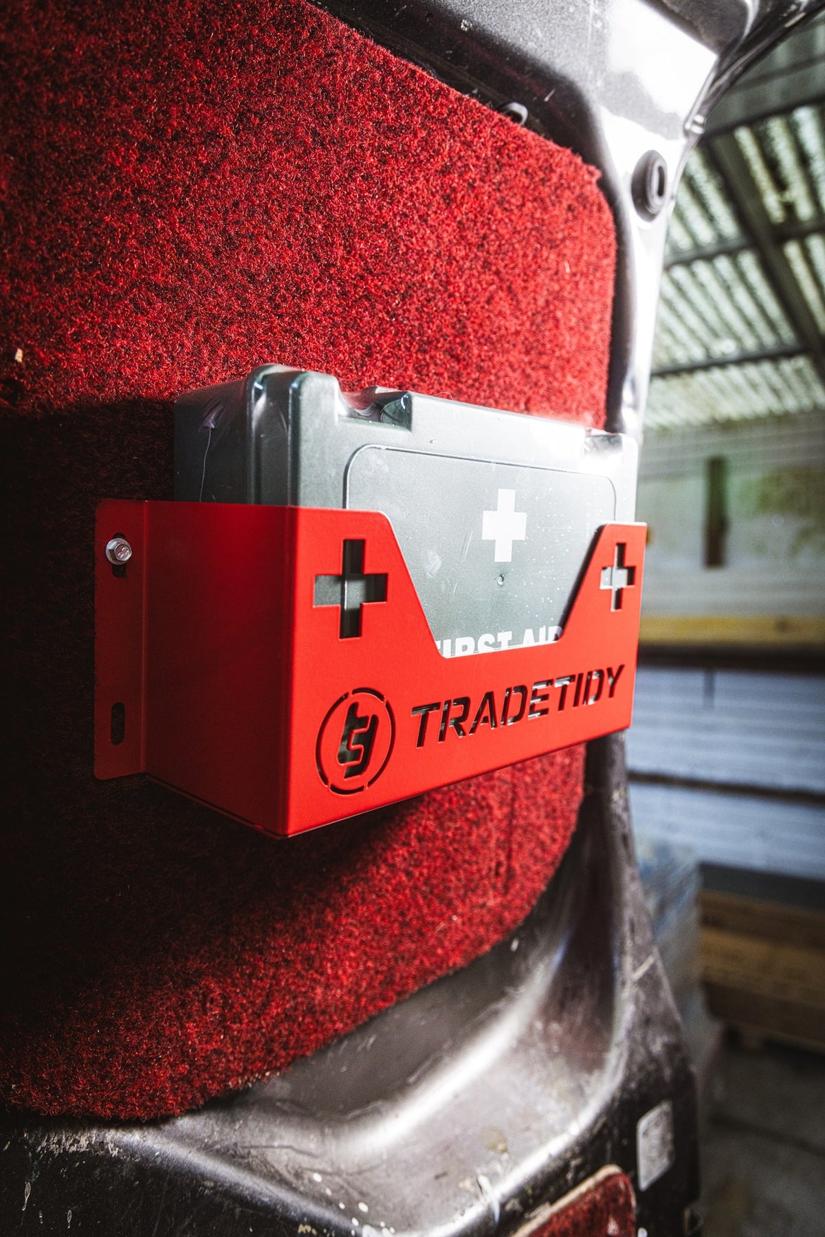 first aid kit in a red first aid kit holder with 'TradeTidy' branding mounted on a workshop van's door