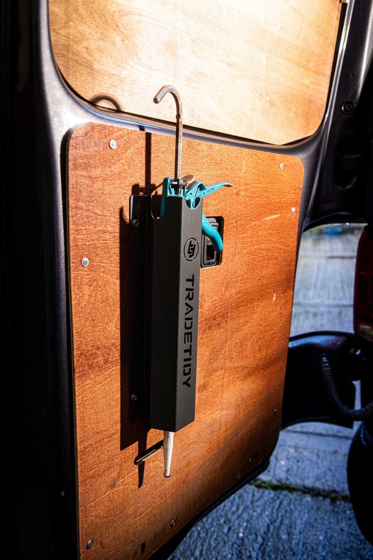 TradeTidy - silicone gun in a black silicone holder mounted on a wooden wall in a workshop van