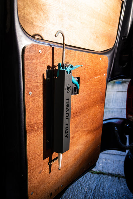 TradeTidy - silicone gun in a black silicone holder mounted on a wooden wall in a workshop van