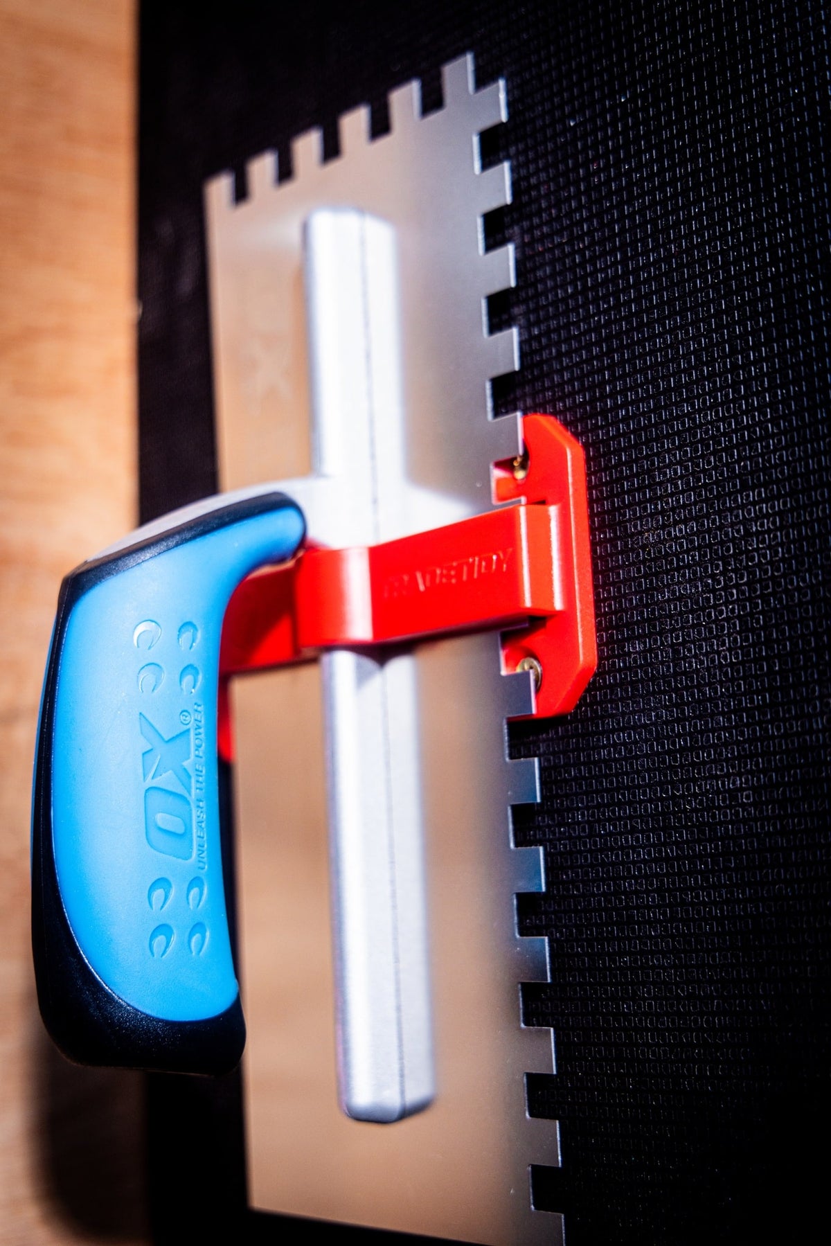 TradeTidy - trowel with a blue handle in a red trowel holder mounted on a wall