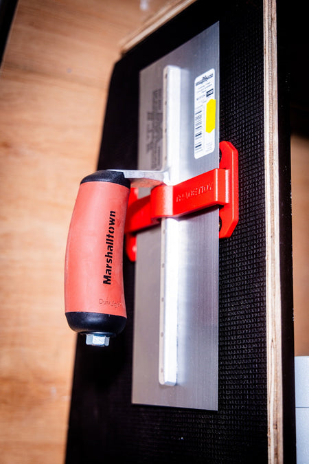 TradeTidy - trowel with an orange handle in a red trowel holder mounted on a wall