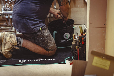 Person working on a project with tools and a TradeTidy work mat and collapsible bucket in a workshop setting.
