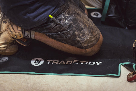 Person wearing work boots on a black work mat with 'TradeTidy' branding.