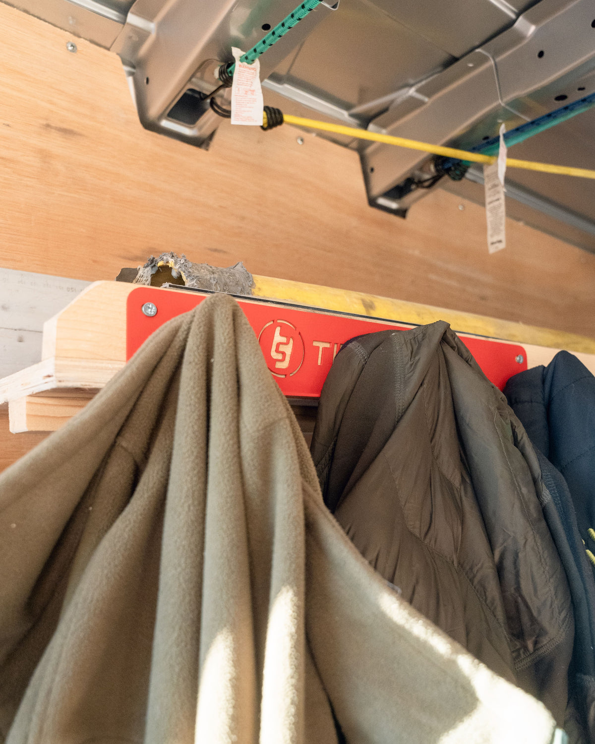 TradeTidy - Red Coat Hanger mounted on a wooden wall with jackets hanging