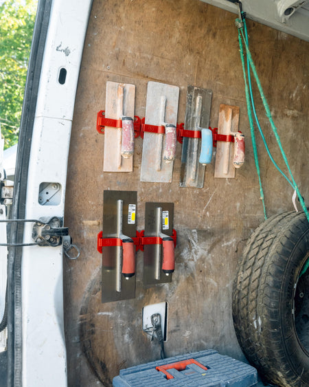 TradeTidy - Trowel Holders mounted on a wall, holding various trowels, with a focus on the holders in the center.