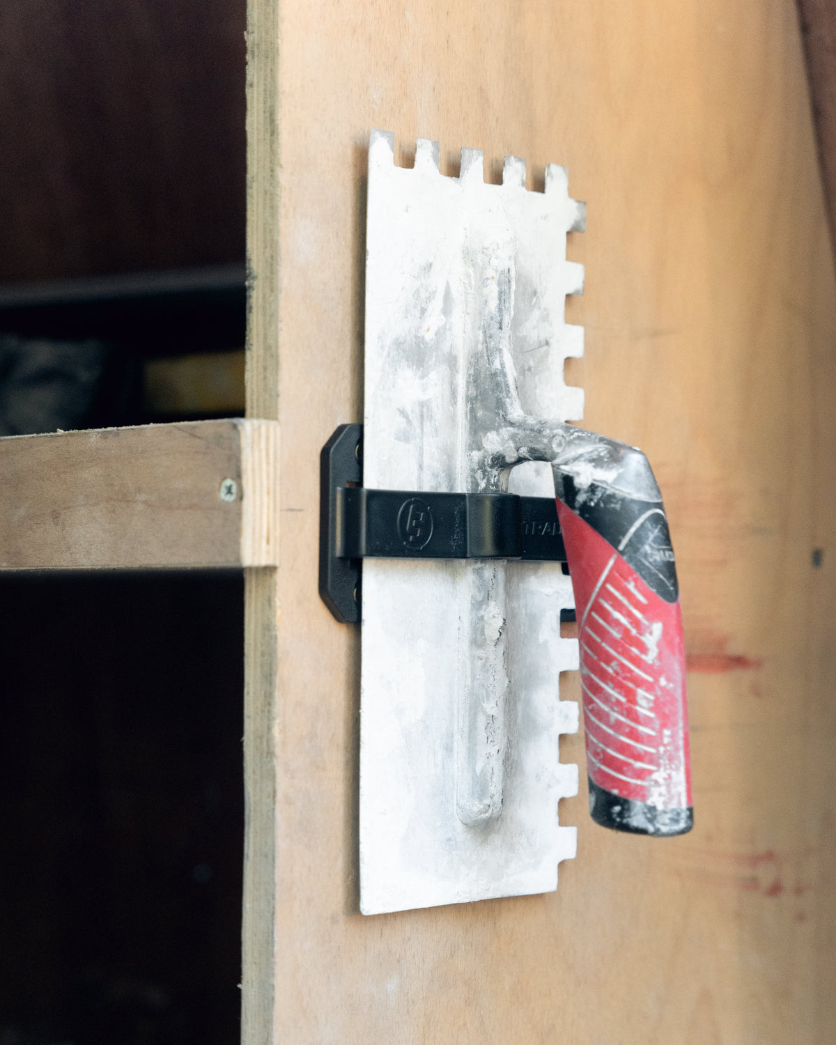 trowel in a trowel TradeTidy holder mounted on a wooden wall