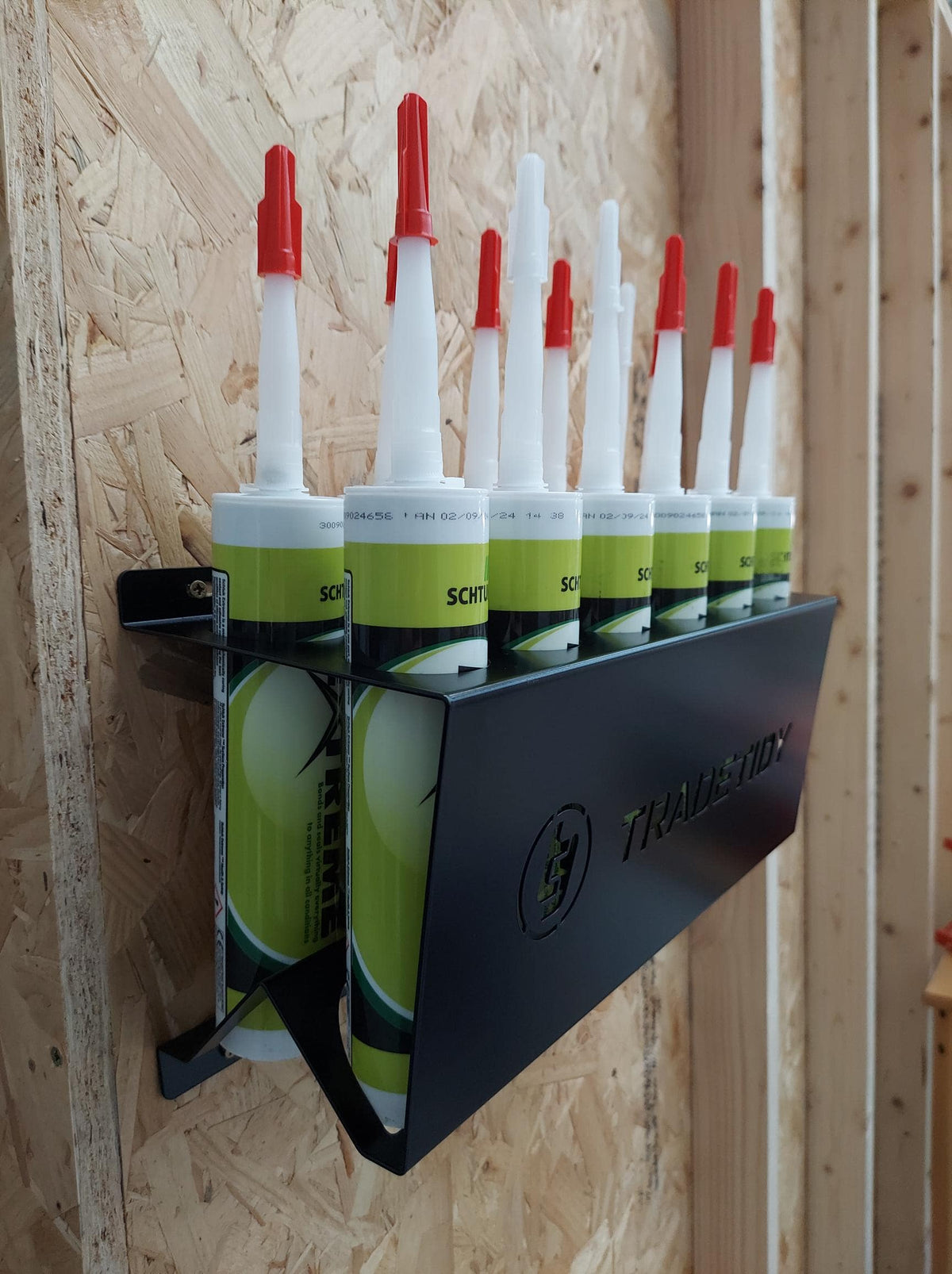 TradeTidy - silicone tubes in a black silicone tube holder hanging on a wooden wall