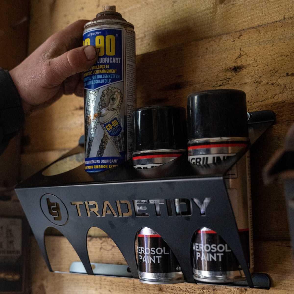 TradeTidy - Hand holding a Can in a black can holder mounted on a wooden wall
